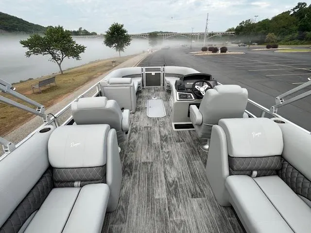 Slide: The Image of 2025 Ranger Reata 243C with Mercury outboard motor, parked near a lake. - 7