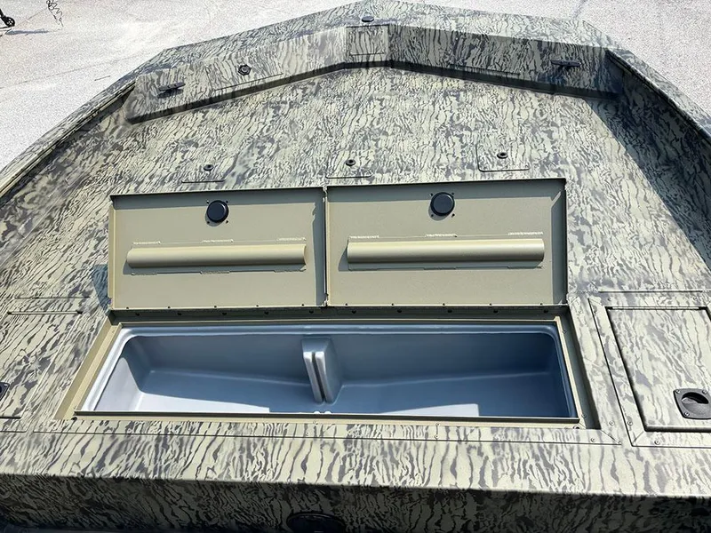 Slide: The Image of 2025 Tracker Grizzly 2072 CC boat with open storage compartments on a textured deck. - 14