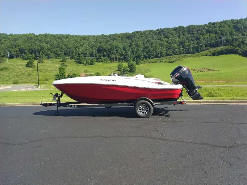 The Image of 2025 Tahoe T18 boat on trailer, parked on asphalt with green hills in background. - 0