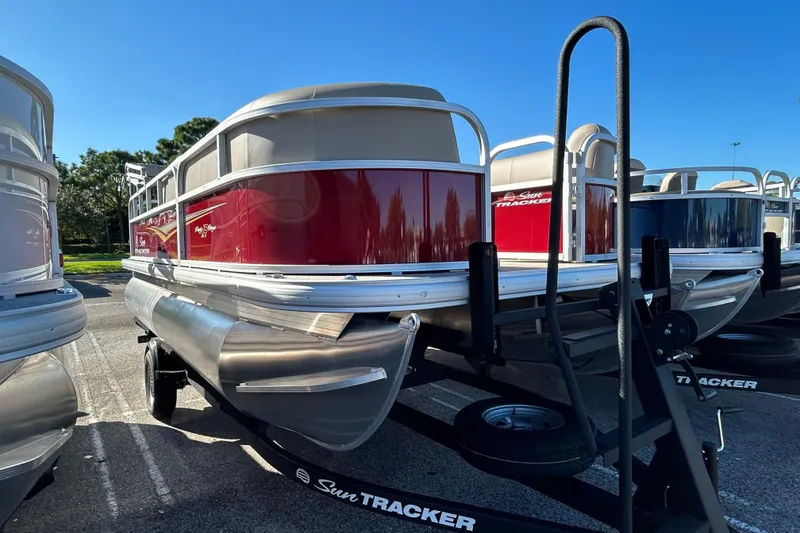 The Image of 2025 Sun Tracker Party Barge 18 DLX pontoon boat on trailer, sunny day. - 0