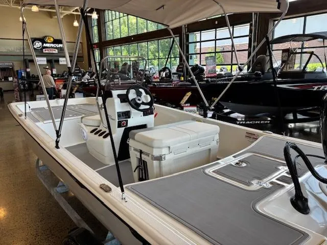 Slide: The Image of 2025 Mako Pro Skiff 17 CC boat displayed in a showroom with canopy and seating. - 5