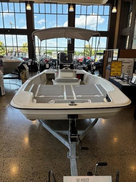 Slide: The Image of 2025 Mako Pro Skiff 17 CC boat displayed indoors with canopy and modern design. - 6