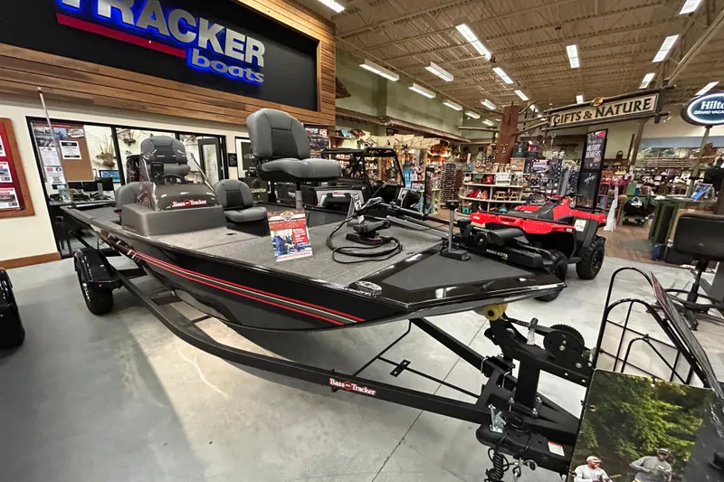 Slide: The Image of 2025 Tracker Bass Tracker Classic XL boat displayed in a showroom with outdoor equipment. - 2