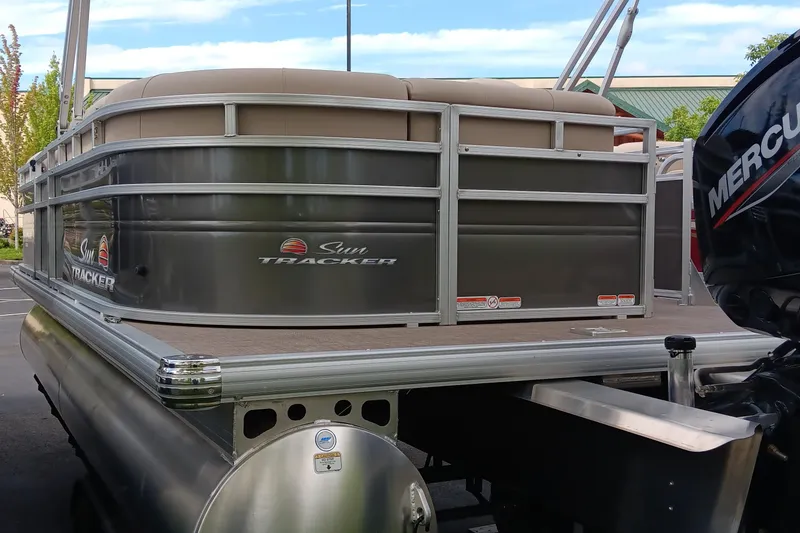 Slide: The Image of 2025 Sun Tracker Party Barge 20 DLX pontoon boat with Mercury engine, docked outdoors. - 2