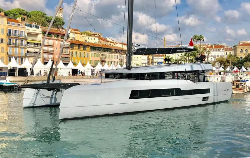 Slide: The Image of Luxurious 2026 McConaghy MC62 catamaran docked in a scenic harbor. - 2