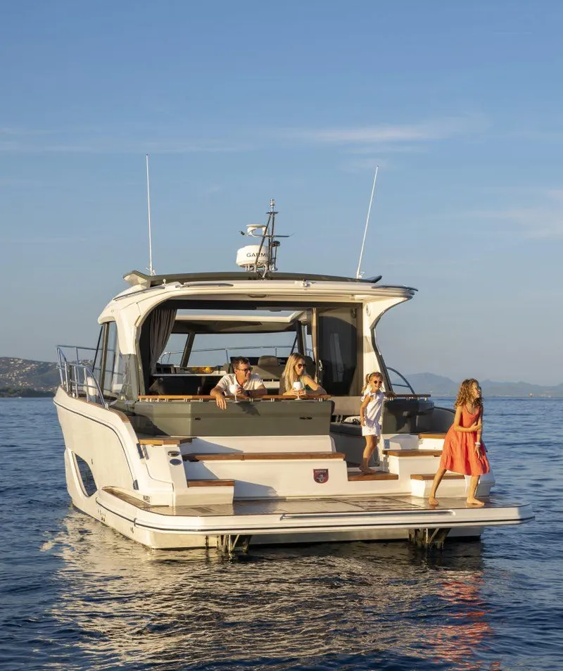 Slide: The Image of 2025 Marex 440 Gourmet Cruiser on serene water with people enjoying the deck. - 24