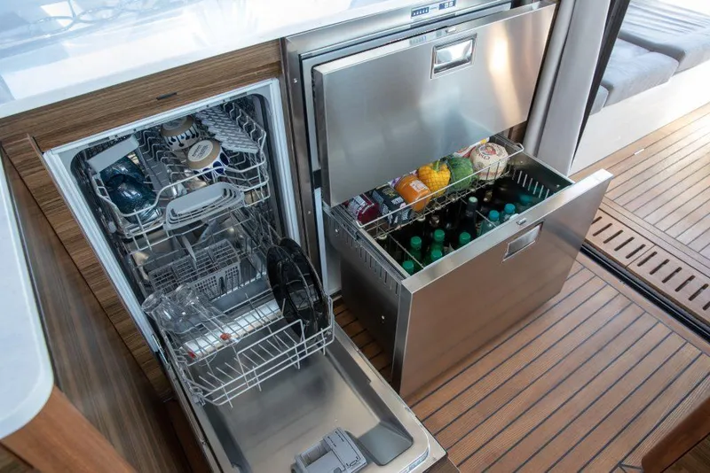 Slide: The Image of 2025 Marex 440 Gourmet Cruiser kitchen with dishwasher and stocked fridge on wooden flooring. - 45