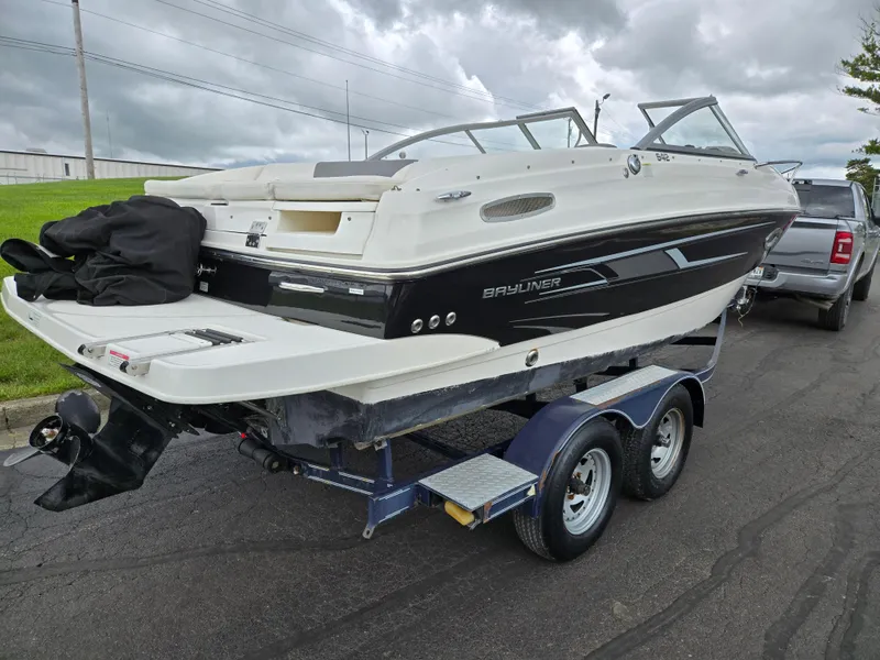 Slide: The Image of 2015 Bayliner 642 Overnighter boat on trailer, parked on a road under cloudy skies. - 3