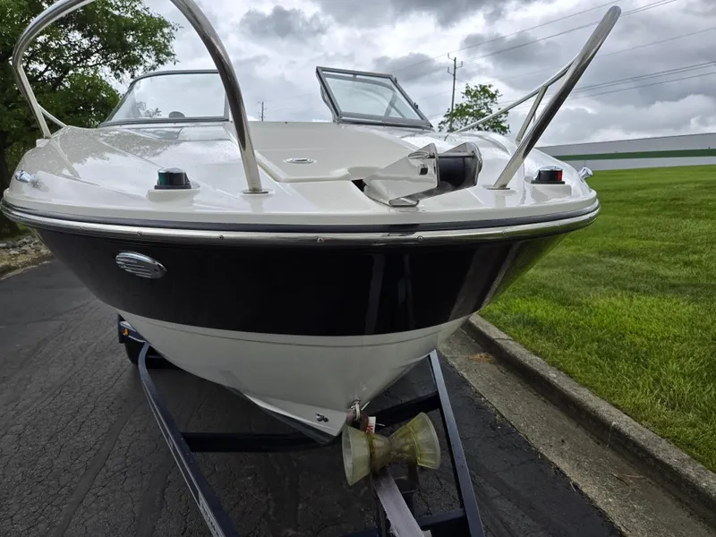 Slide: The Image of 2015 Bayliner 642 Overnighter boat on trailer, parked on paved road, cloudy sky background. - 6