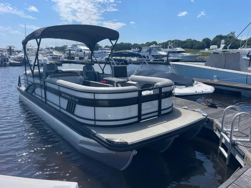 Slide: The Image of 2021 Bennington 24LSR pontoon boat docked at marina under clear blue sky. - 0