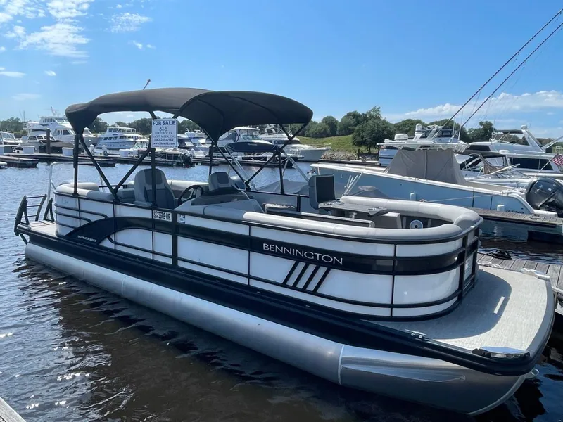 Slide: The Image of 2021 Bennington 24LSR pontoon boat docked at marina under clear blue sky. - 1