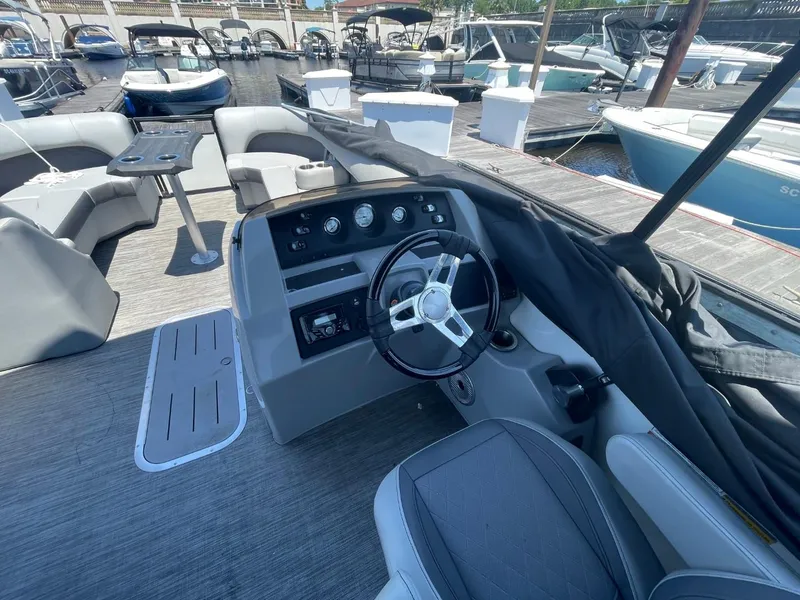 Slide: The Image of 2021 Bennington 24LSR boat interior with steering wheel and seating at a marina. - 10