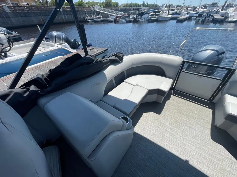 Slide: The Image of 2021 Bennington 24LSR pontoon boat interior with gray seating, docked at a marina. - 14