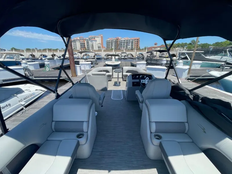 Slide: The Image of Interior of 2021 Bennington 24LSR pontoon boat at marina, featuring spacious seating and canopy. - 18