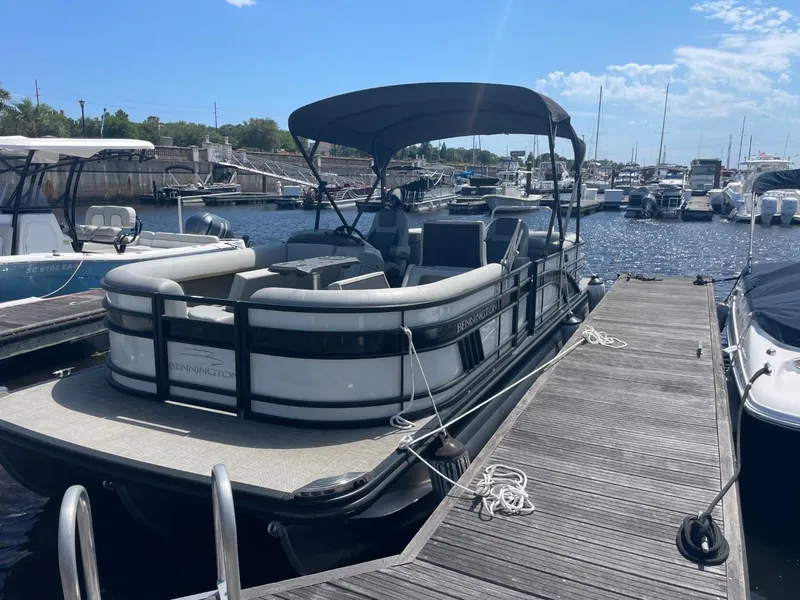 Slide: The Image of 2021 Bennington 24LSR pontoon boat docked at a marina under a sunny sky. - 2