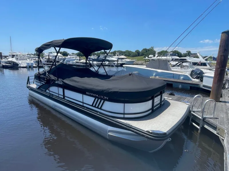 Slide: The Image of 2021 Bennington 24LSR pontoon boat docked at marina under clear blue sky. - 3