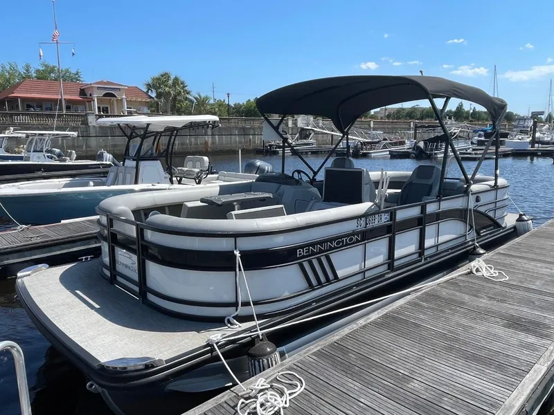 Slide: The Image of 2021 Bennington 24LSR pontoon boat docked at marina under clear blue sky. - 4