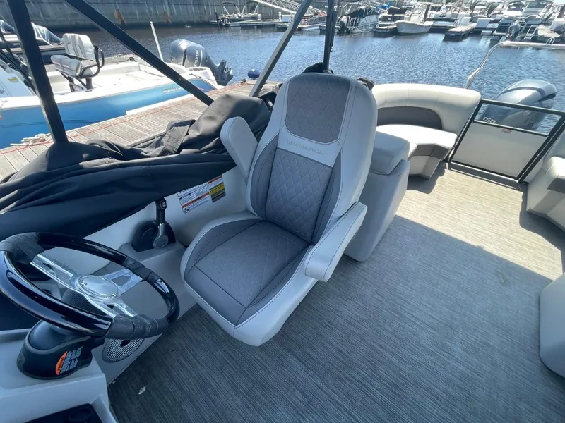 Slide: The Image of 2021 Bennington 24LSR pontoon boat interior with helm seat and steering wheel, docked at marina. - 8