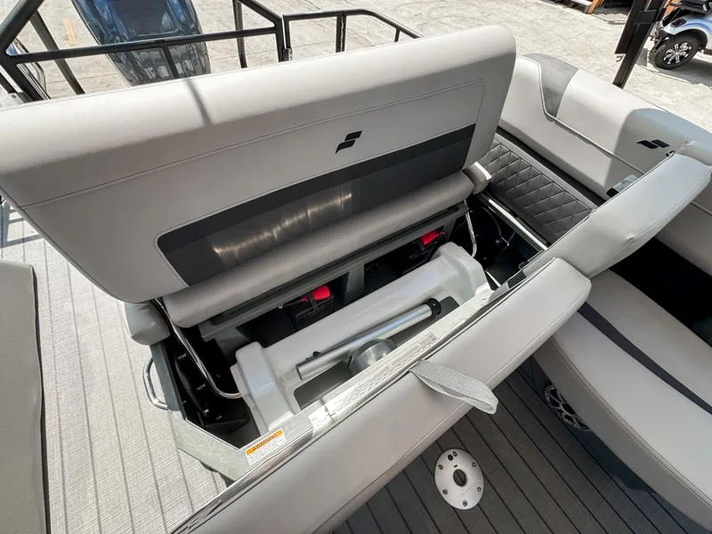 Slide: The Image of 2024 Starcraft CX 23 Q DH boat interior with open storage compartment and gray seating. - 11
