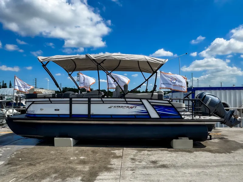 Slide: The Image of 2024 Starcraft CX 23 Q DH pontoon boat with canopy, displayed outdoors under blue sky. - 2
