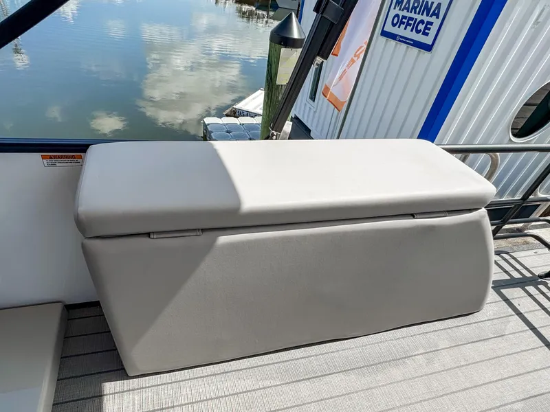 Slide: The Image of 2024 Starcraft CX 23 Q DH boat seat near marina office, reflecting on water. - 26