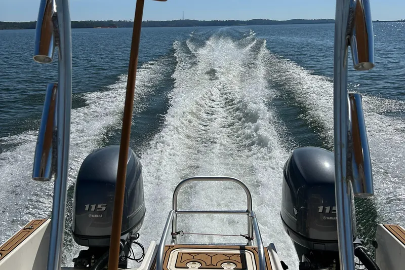 Slide: The Image of 2013 Carolina Cat 230 CC boat cruising on open water, twin Yamaha 115 engines visible. - 6