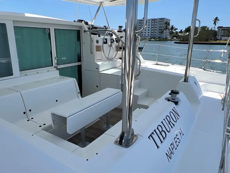 Slide: The Image of 2008 Lagoon 420 catamaran deck with seating, steering wheel, and waterfront view. - 17