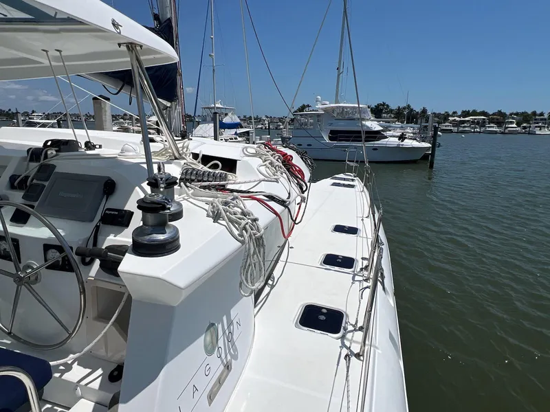Slide: The Image of 2008 Lagoon 420 catamaran docked at marina, featuring steering wheel and rigging. - 26