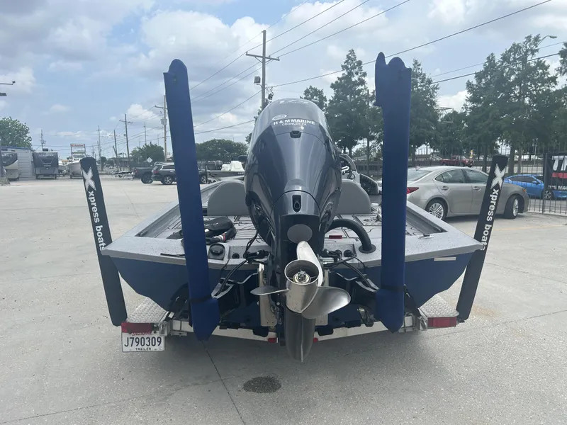 Slide: The Image of 2021 Xpress X19 Pro boat with outboard motor, parked in a lot under cloudy skies. - 6