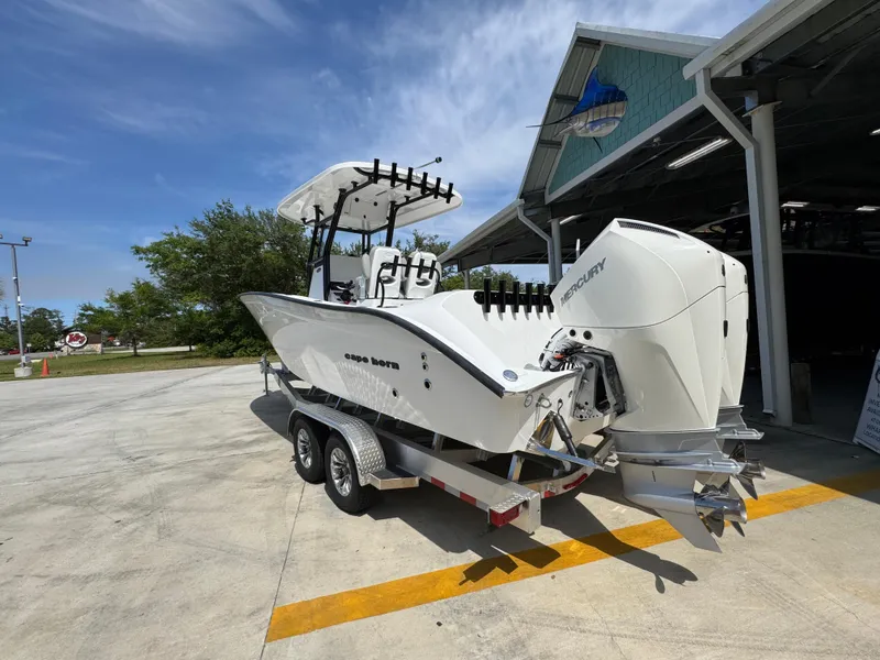 Slide: The Image of 2025 Cape Horn 27 XS boat on trailer, parked outside a building under a clear sky. - 15