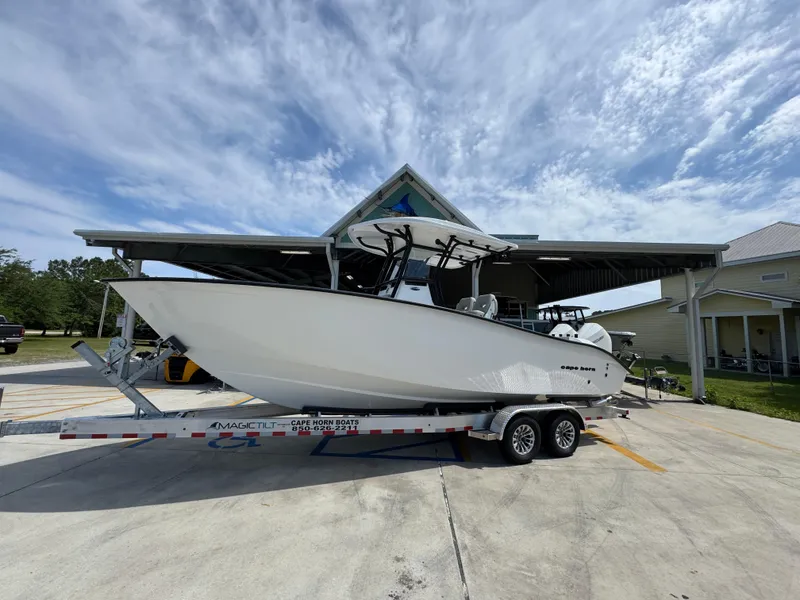 Slide: The Image of 2025 Cape Horn 27 XS boat on trailer under a canopy, clear sky background. - 2