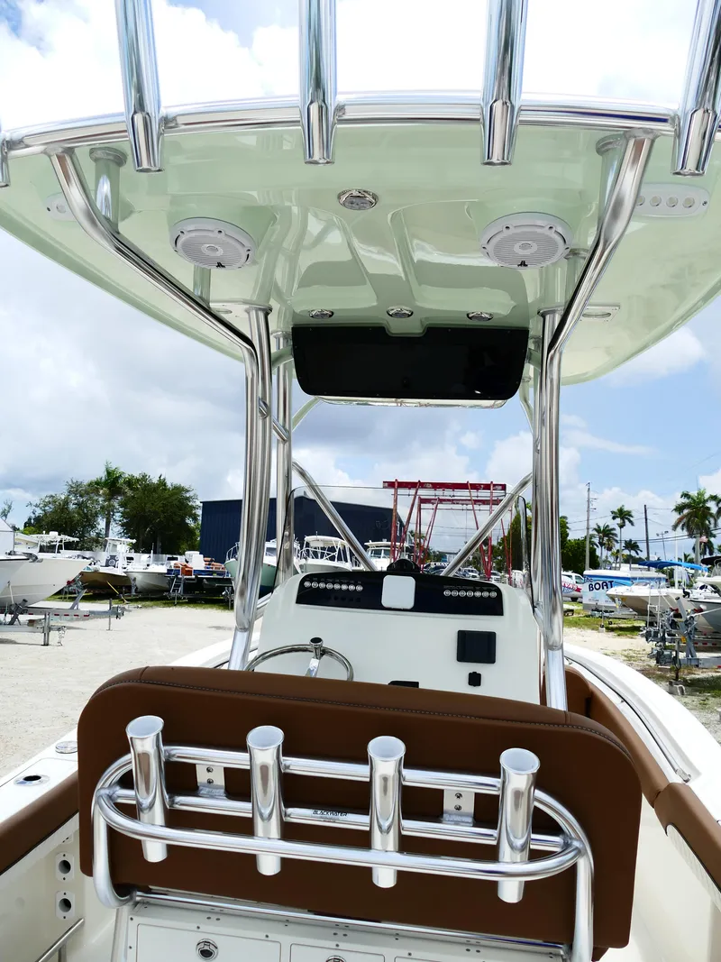 Slide: The Image of 2026 Pioneer 222 Islander boat interior with rod holders and T-top, parked outdoors. - 11