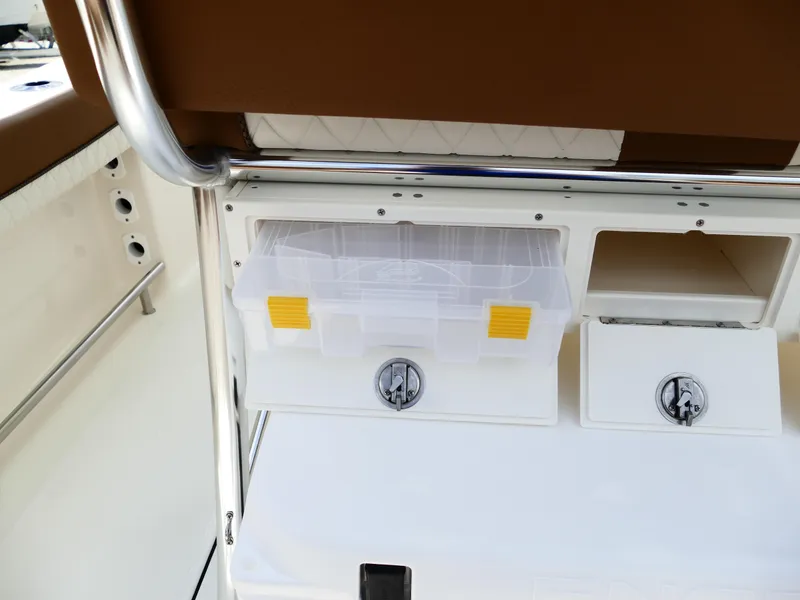 Slide: The Image of 2026 Pioneer 222 Islander boat storage compartment with clear tackle box and secure latches. - 16