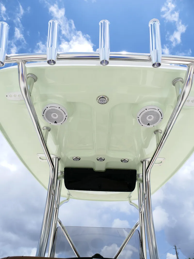 Slide: The Image of 2026 Pioneer 222 Islander boat T-top with rod holders and speakers against blue sky. - 19