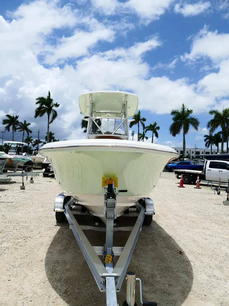 Slide: The Image of 2026 Pioneer 222 Islander boat on trailer, parked under a partly cloudy sky with palm trees. - 2