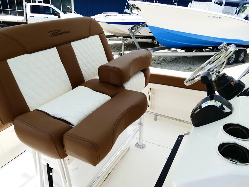 Slide: The Image of 2026 Pioneer 222 Islander boat interior with brown and white seating, steering wheel, and controls. - 31