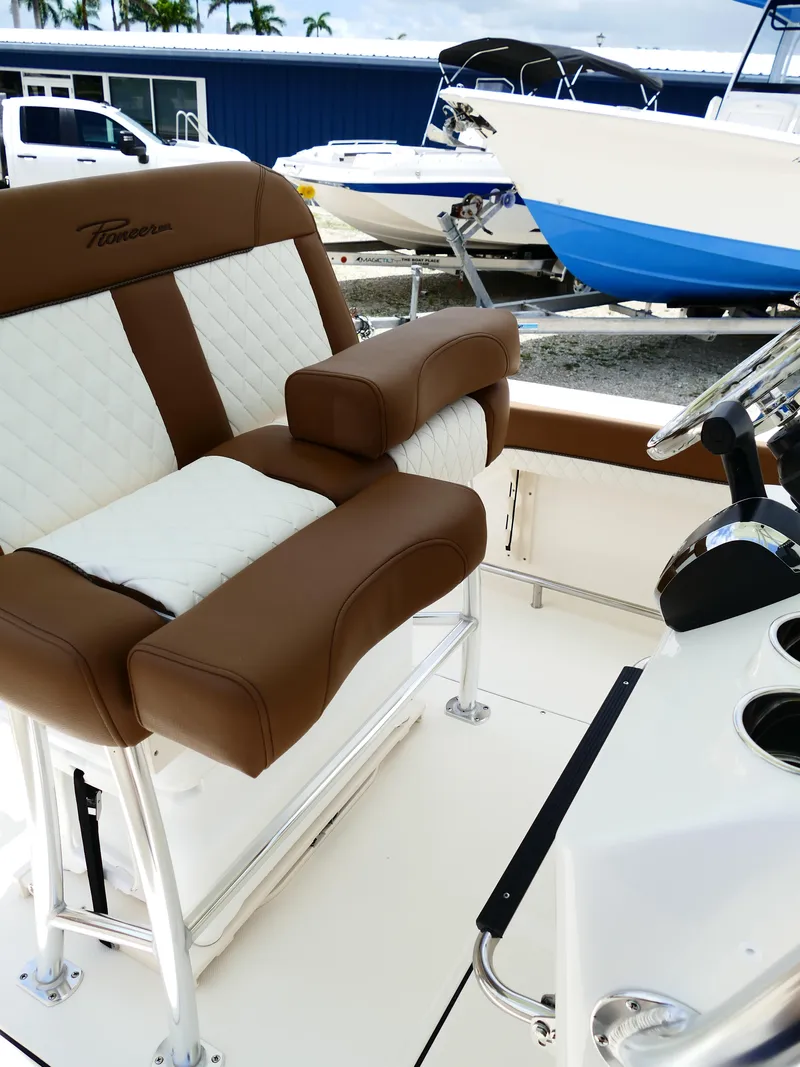 Slide: The Image of 2026 Pioneer 222 Islander boat interior with brown and white seating, steering wheel, and cup holders. - 32