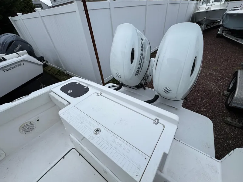 Slide: The Image of 2024 Clearwater 2500 boat with dual Suzuki outboard motors, parked near a white fence. - 2
