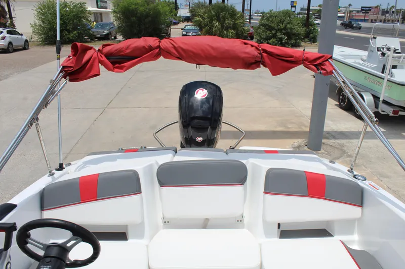 Slide: The Image of 2023 Tahoe T18 boat interior with red canopy and seating, parked outdoors. - 11