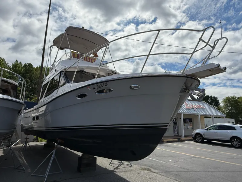 Slide: The Image of 2023 Cutwater C-32 CB boat on display, elevated on stands, under a cloudy sky. - 2