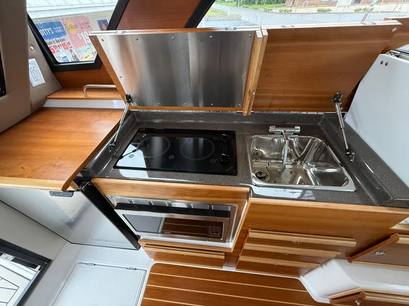 Slide: The Image of 2023 Cutwater C-32 CB galley with stove, sink, and wooden cabinetry. - 34