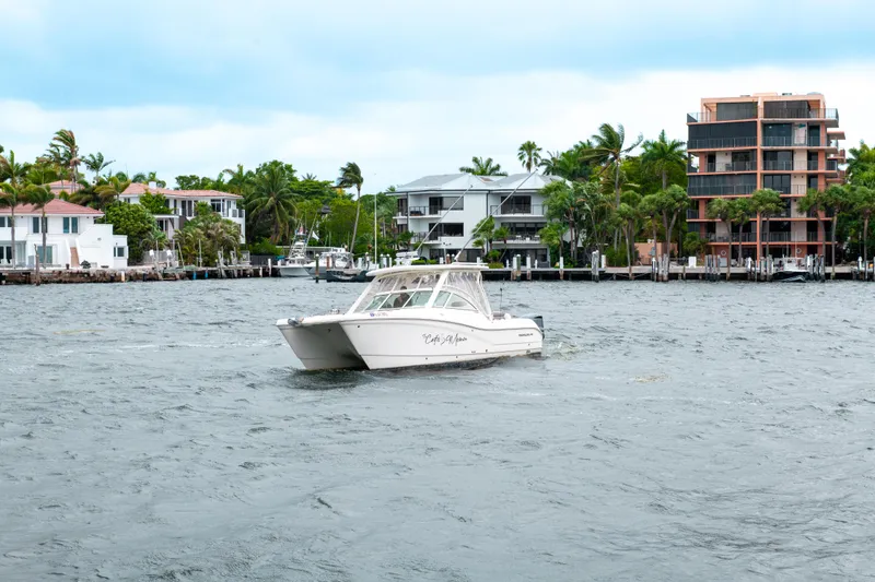 Slide: The Image of 2019 World Cat 296DC boat cruising near waterfront homes and palm trees. - 10