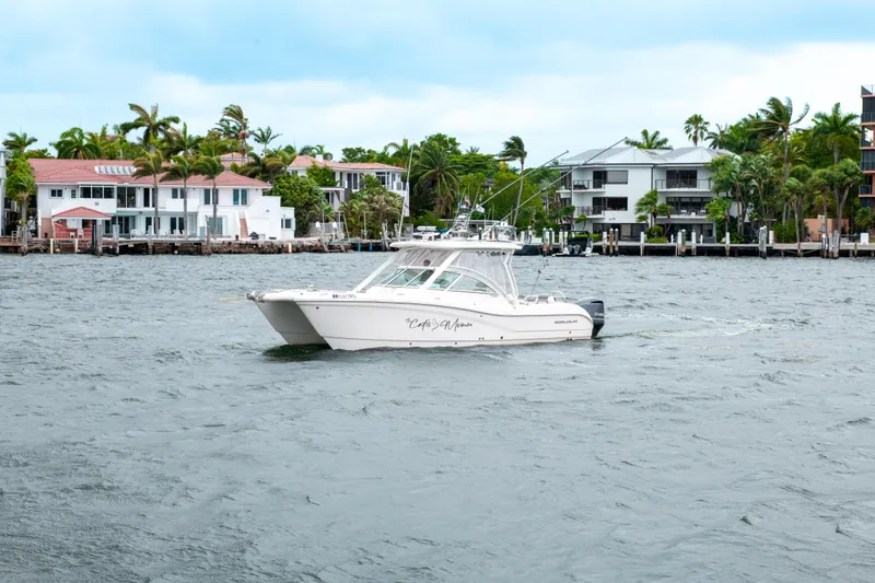 Slide: The Image of 2019 World Cat 296DC boat cruising near waterfront homes with palm trees. - 12
