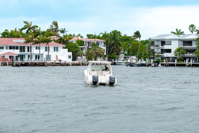 Slide: The Image of World Cat 296DC boat cruising near waterfront homes, 2019 model. - 19