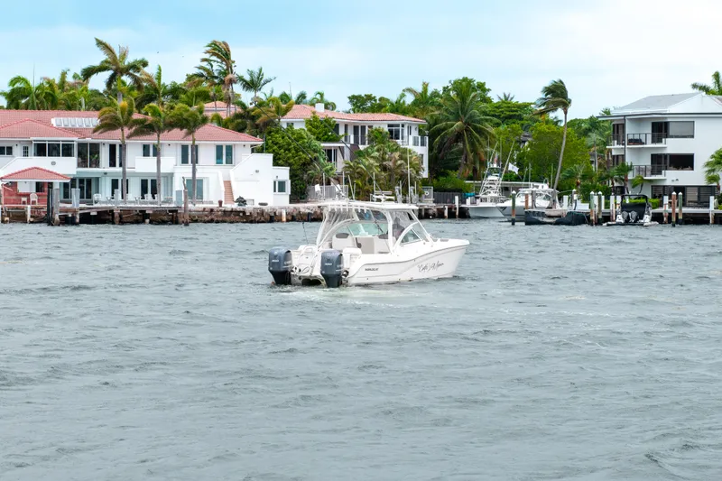 Slide: The Image of 2019 World Cat 296DC boat on water near waterfront homes and palm trees. - 21