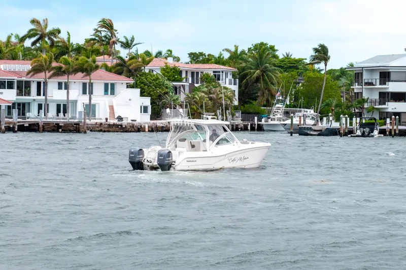 Slide: The Image of 2019 World Cat 296DC boat cruising near waterfront homes with palm trees. - 22