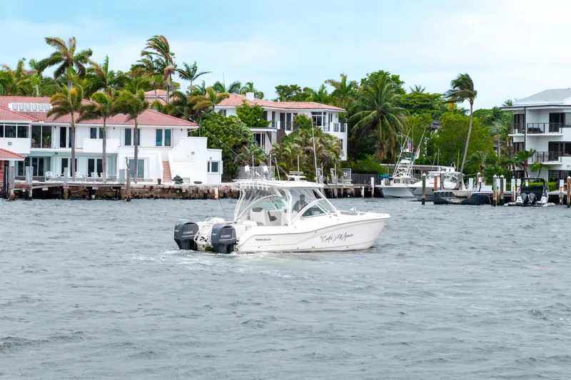 Slide: The Image of 2019 World Cat 296DC boat cruising near waterfront homes and palm trees. - 23