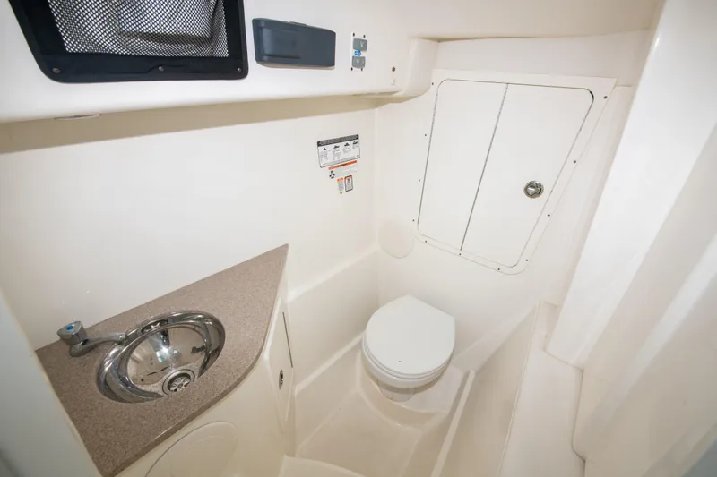 Slide: The Image of 2019 World Cat 296DC boat interior with compact bathroom, featuring a sink and toilet. - 32
