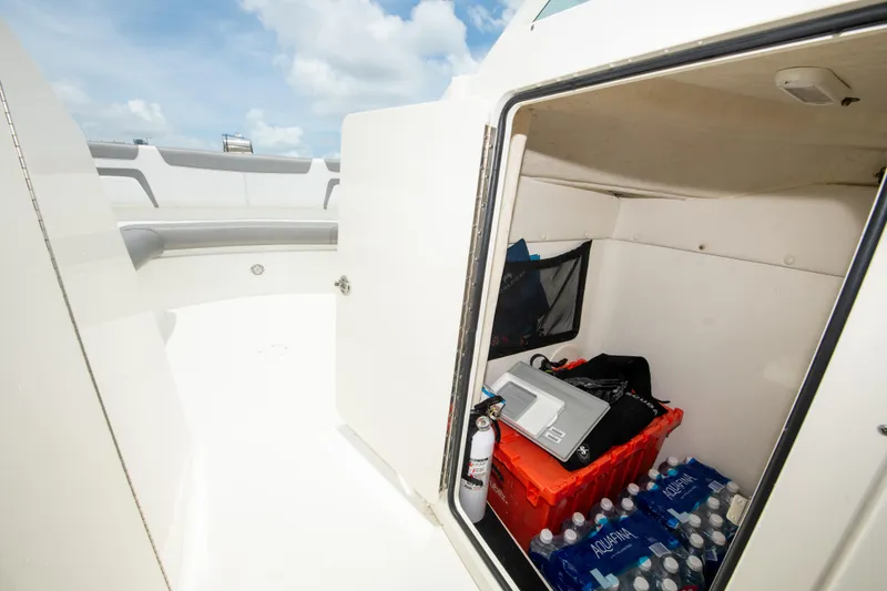 Slide: The Image of Storage compartment on a 2019 World Cat 296DC boat, stocked with supplies and water bottles. - 33