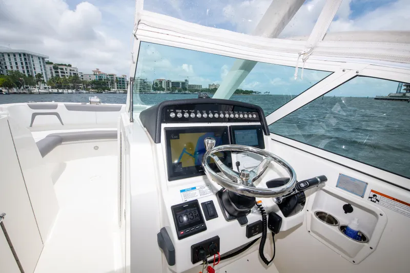 Slide: The Image of 2019 World Cat 296DC boat helm with steering wheel and navigation controls. - 34